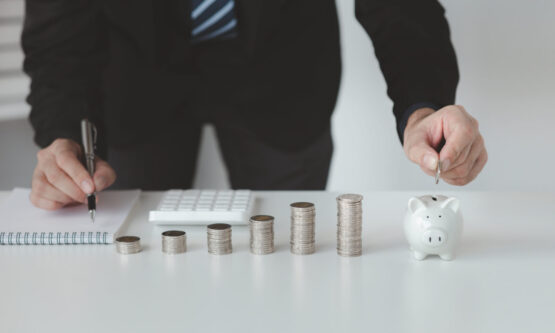 Person with pile of coins and piggy bank, money saving concept f