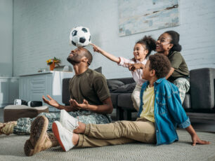 Woman and man in army uniform with their children playing with football ball
